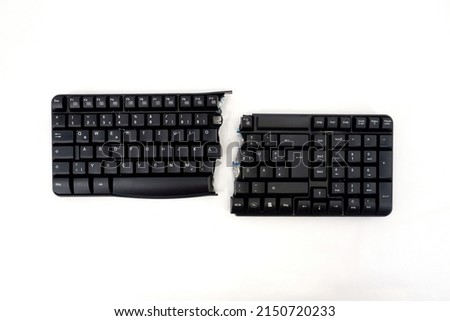 PC keyboard is cut into two parts. A black computer keyboard broken in half with an English Qwerty layout , isolated on a white background . View from above. Royalty-Free Stock Photo #2150720233