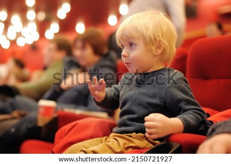 Cute toddler boy watching cartoon movie in the cinema. Leisureentertainment for family with kids.