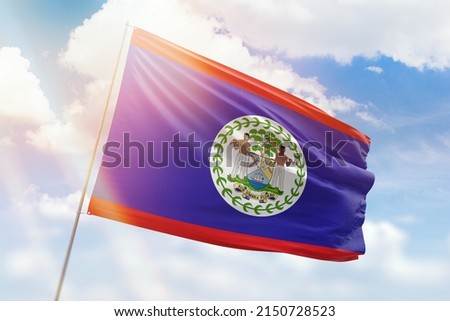 Sunny blue sky and a flagpole with the flag of belize