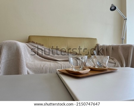 two empty cup of coffee serve on the wooden tray in the background of empty sofa that have blanket on it