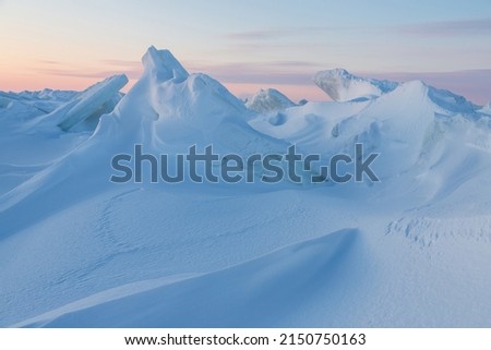 Winter arctic landscape. View of snow and ice at sunset. Ice hummocks on the frozen sea in the Arctic. Cold frosty winter weather. Harsh polar climate. Travel and hikes to the far north to the Arctic. Royalty-Free Stock Photo #2150750163