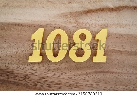 Wooden  numerals 1081 painted in gold on a dark brown and white patterned plank background.