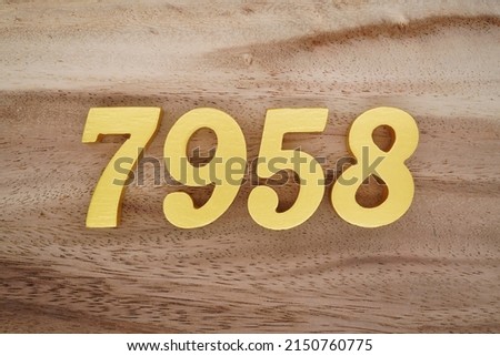 Wooden  numerals 7958 painted in gold on a dark brown and white patterned plank background.