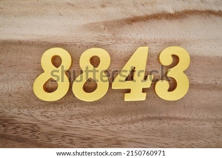 Wooden  numerals 8843 painted in gold on a dark brown and white patterned plank background.