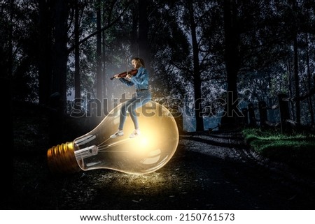 Girl plays on violin sitting on light bulb