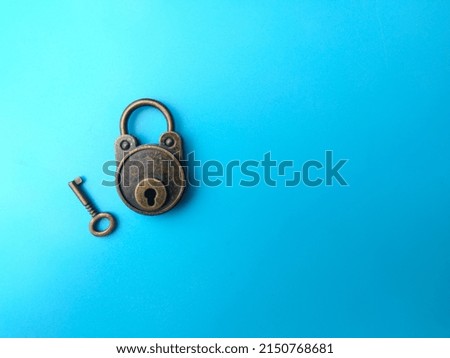 Selective focus.Vintage bronze key and padlock on soft blue paper, background image with copy and text space.