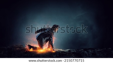 Determined businessman leaving fire trails on asphalt . Mixed media Royalty-Free Stock Photo #2150770715