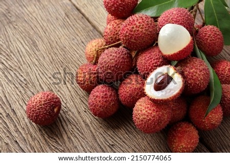 Fresh ripe lychee fruit and peeled lychee with green leaves on wooden background. rustic style, from above Royalty-Free Stock Photo #2150774065