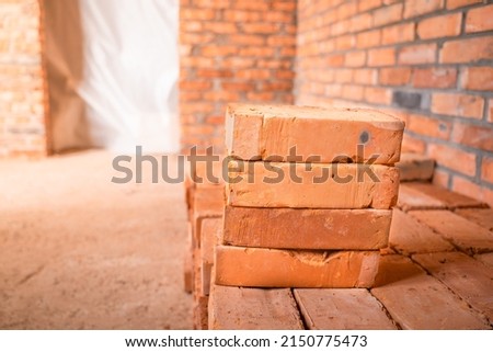 Red bricks stacked at a construction site, close-up. The bare brick walls of an unworthy house. The doorway is closed with polythene film Royalty-Free Stock Photo #2150775473