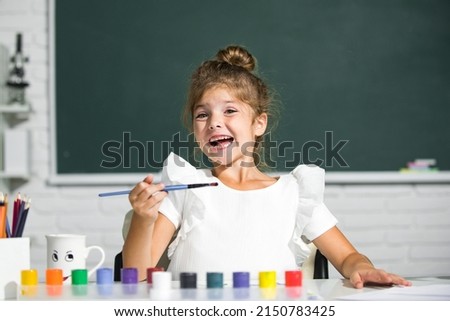Little girls drawing a colorful pictures with pencil crayons in school classroom. Painting kids. Funny kids emotions.