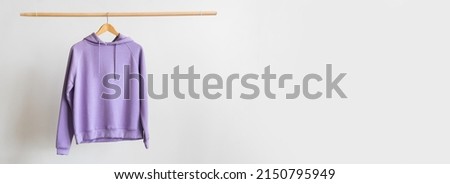 Modern hoodie hanging on light background with space for text