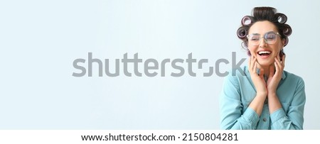 Beautiful happy young woman in hair rollers on light background with space for text
