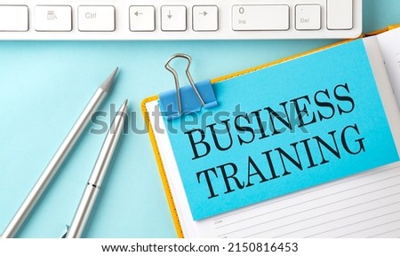 BUSINESS TRAINING text on a blue sticker on the planning and keyboard,blue background