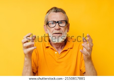 Portrait of happy senior man wearing glasses yellow shirt posing unaltered