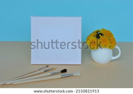 Dandelion bouquet in a vase and picture frame with copy space for mockup on a blue background. A set of brushes for drawing