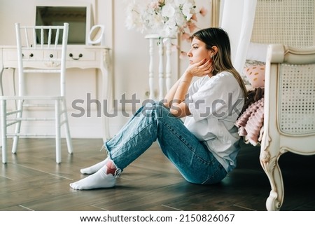 Young bored millennial woman sitting on a floor alone at home. Fatigue or emotionally exhausted concept