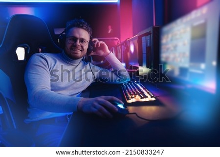 Portrait Streamer young man professional gamer playing online games computer with headphones, neon color.