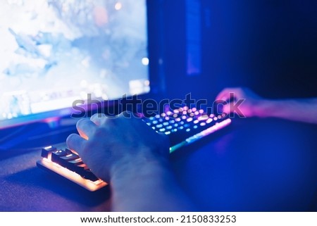 Selective focus arm hand on keyboard of computer with neon illumination for cyber sports, professional game.
