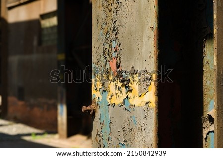 Cracked and aged layers of paint on an iron supporting beam of an abandoned industrial building