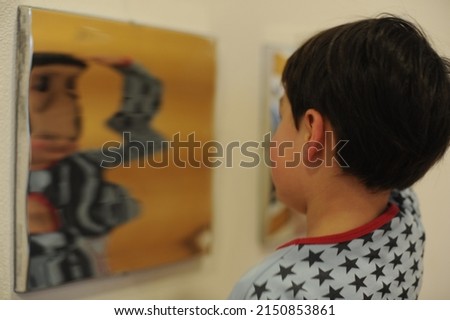 A child boy reflected in diverging mirror, spherical mirror creating optical illusion of distorted face and shape on the surface of glass Royalty-Free Stock Photo #2150853861