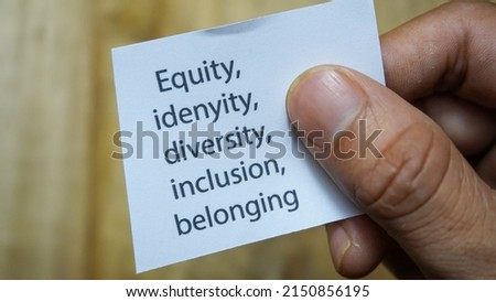 Equity, identity, diversity, inclusion, belonging. Man holding a paper note message with the written word "Equity, identity, diversity, inclusion, belonging". Businessman's hand. Business, signs.