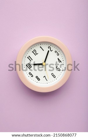 Pink clock on purple background. Vertical photo
