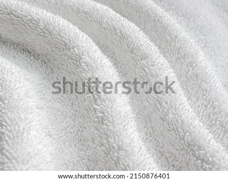 White background of towel texture. White towel lies in twisted beautiful folds. Macro photo of terry cloth or beach towel. Soft textile background. Royalty-Free Stock Photo #2150876401