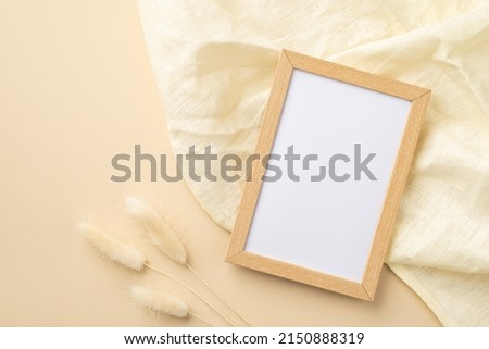 Top view photo of wooden photo frame linen and white lagurus flowers on isolated beige background with copyspace