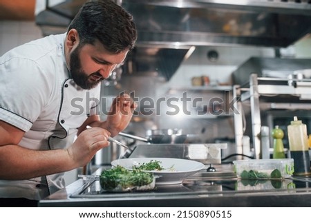 Some additional ingredients. Professional chef preparing food in the kitchen.