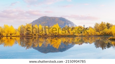 A good place for fishing and recreation. A picturesque pond in autumn with a lonely mountain in the background Royalty-Free Stock Photo #2150904785