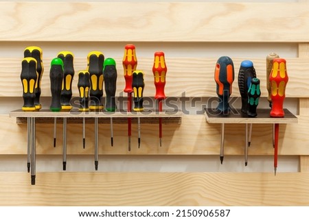 Screwdrivers in workshop. Set of Screw Drivers. Multicolored screwdrivers hanged on shelf.  Royalty-Free Stock Photo #2150906587
