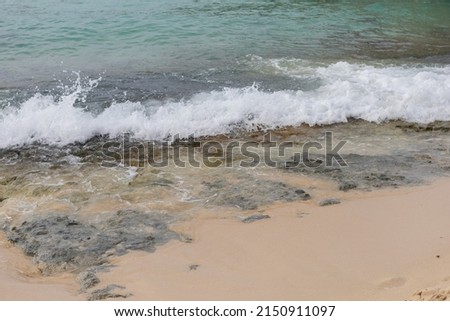 A sea wave runs onto the shore and breaks on small rocks.A fragment of the seashore with rocks covered with algae.Beautiful color of water in the Caribbean Sea of the Dominican Republic