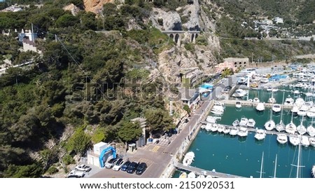 An aerial shot of the port of Alassio with yachts next to the town on a sunny day