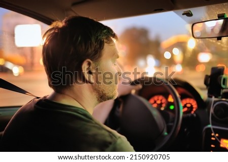 Male driver ride a car during evening traffic jam. Drive in the night city. Inside view.