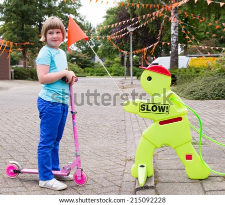 Girl on scooter with safety figurine as warning sign
