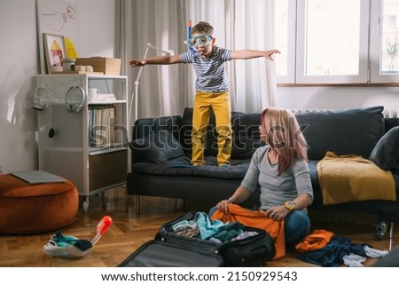 mother and son having great time while packing bags for summer vacation Royalty-Free Stock Photo #2150929543