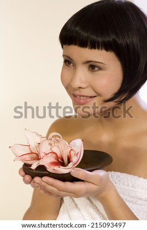 Young woman holding bowl with orchid blossoms, portrait