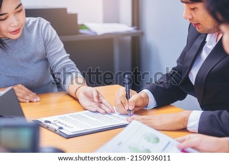 Businessman puts signature on contract at business meeting and passing money after negotiations with business partners. Selected focus