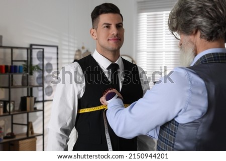 Professional tailor measuring client's chest circumference in atelier Royalty-Free Stock Photo #2150944201