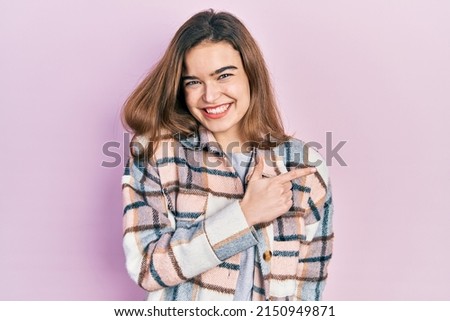Young caucasian girl wearing casual clothes cheerful with a smile on face pointing with hand and finger up to the side with happy and natural expression 