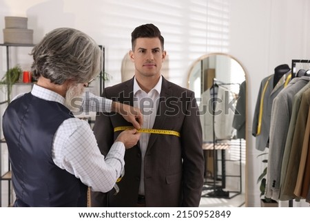 Professional tailor measuring client's chest circumference in atelier Royalty-Free Stock Photo #2150952849