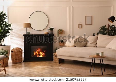 Stylish living room interior with electric fireplace, comfortable sofa and beautiful decor elements Royalty-Free Stock Photo #2150952887