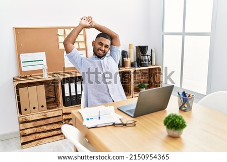 Young middle east man smiling confident stretching arms at office