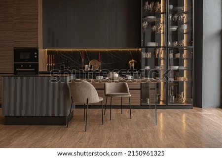 kitchen veiw of a chic modern design of a dark expensive interior of a luxurious country house with huge panoramic windows and a magnificent view of the divine forest Royalty-Free Stock Photo #2150961325