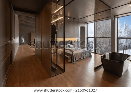 chic modern design of a dark expensive interior of a luxurious country house with huge panoramic windows and a magnificent view of the divine forest Royalty-Free Stock Photo #2150961327