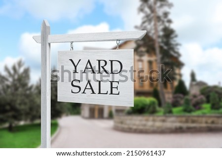 Sign with text YARD SALE and blurred view of beautiful house