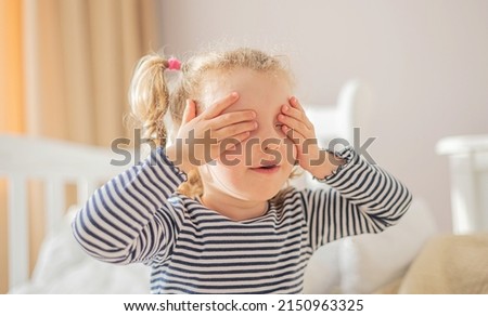 The little girl covered her eyes with her hands.