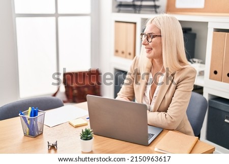 Young blonde woman business worker using laptop and earphones at office