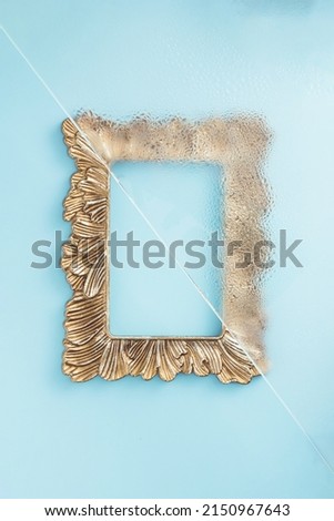 Retro picture frame partly under steamed glass on a blue background. Minimal flat lay concept.