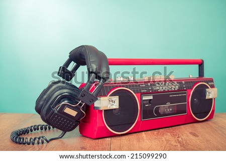 Retro headphones and red radio tape recorder on table